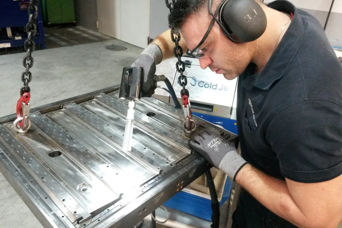 Operator cleans an injection mold with Cold Jet dry ice blasting; Cold Jet machine visible